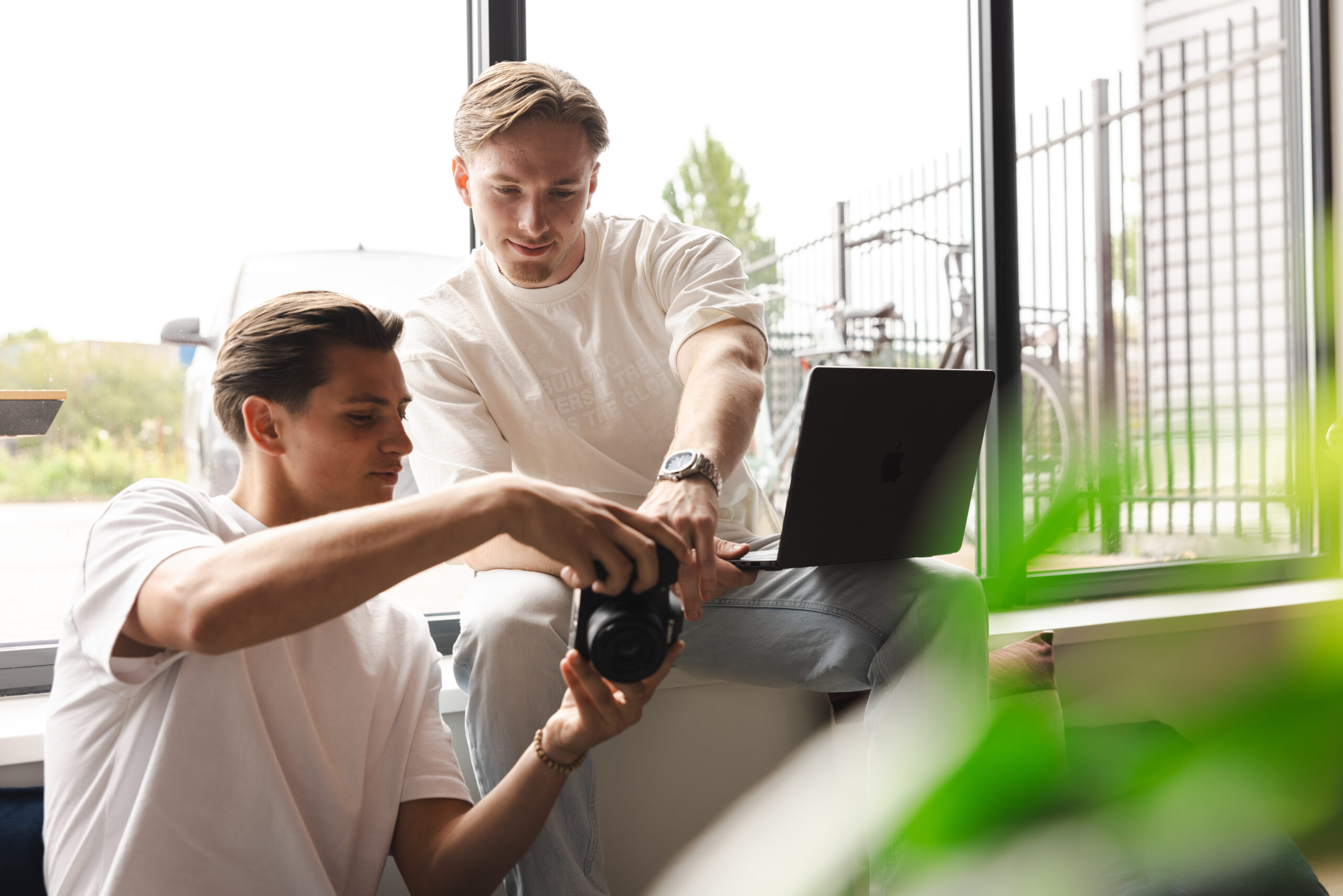 2 collega's met een camera en een laptop op schoot